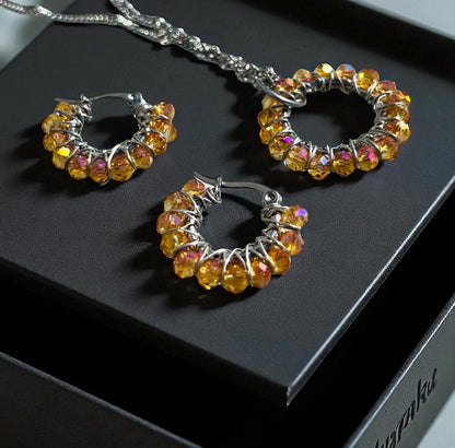 Set Iskrivý Oheň – ručne robené šperky so sklenenými brúsenými korálikmi Harakka Jewls
	2.	Ohnivé kruhové náušnice so zlatými sklenenými korálikmi
	3.	Prívesok so symbolom kruhu – Harakka Jewls
	4.	Elegantný set šperkov v darčekovej krabičke Harakka
