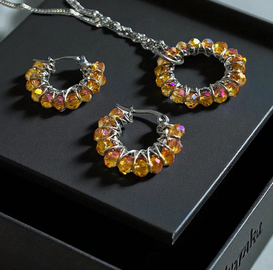 Set Iskrivý Oheň – ručne robené šperky so sklenenými brúsenými korálikmi Harakka Jewls
	2.	Ohnivé kruhové náušnice so zlatými sklenenými korálikmi
	3.	Prívesok so symbolom kruhu – Harakka Jewls
	4.	Elegantný set šperkov v darčekovej krabičke Harakka
