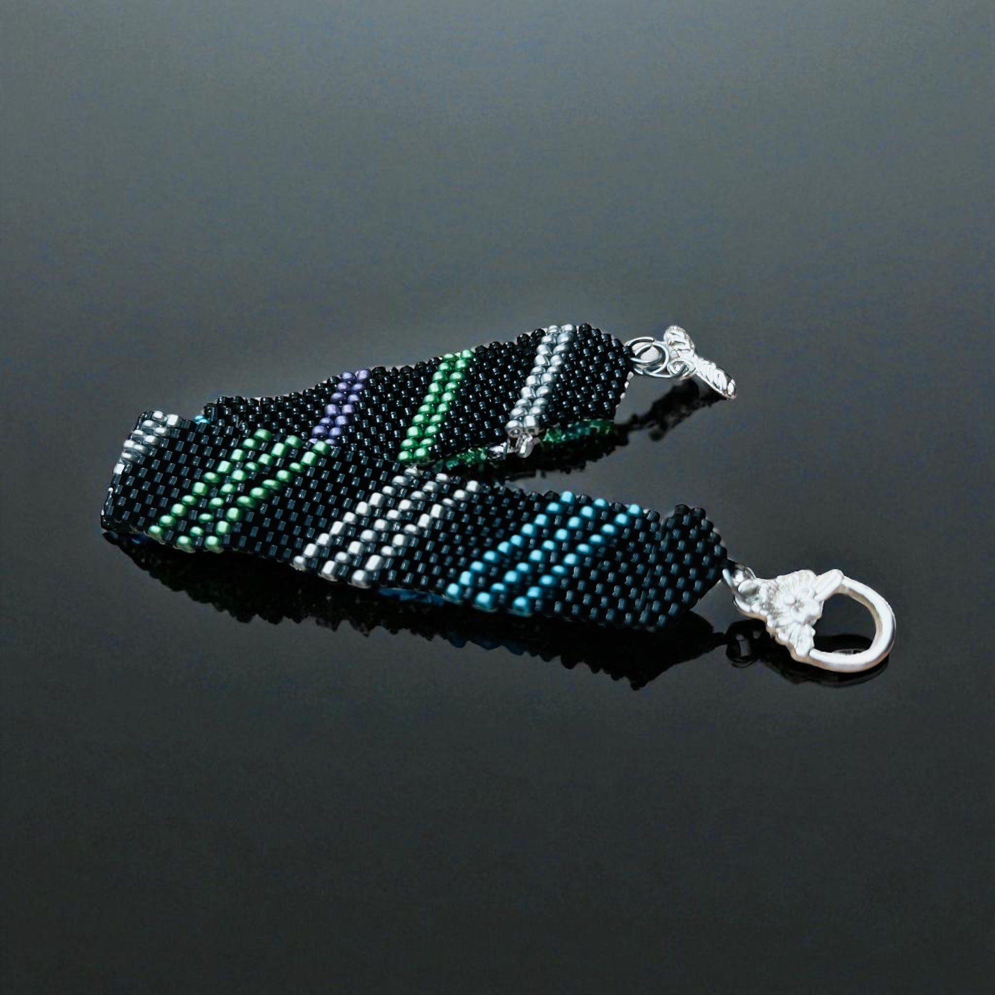 Náramok Nočný prúd – ručne šitý čierny náramok s fialovými, striebornými, tyrkysovými a zelenými korálikmi | Harakka Jewls