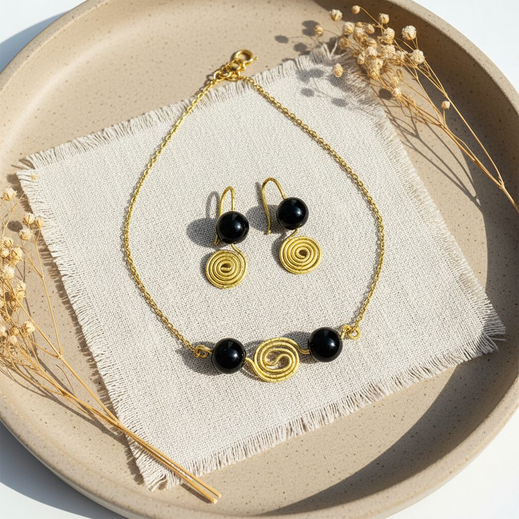 Flat lay set náhrdelnika a náušníc s obsidiánom a zlatou špirálou na ľanovej látke – Harakka Jewls