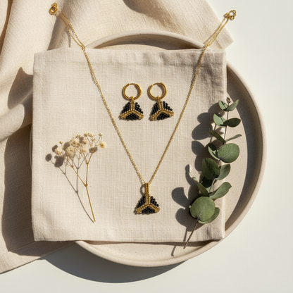 Čierno-zlatý set šperkov Zlatý trojuholník sily na krémovom ľane so sušenými kvetmi – minimalistický luxusný flat lay Harakka Jewls