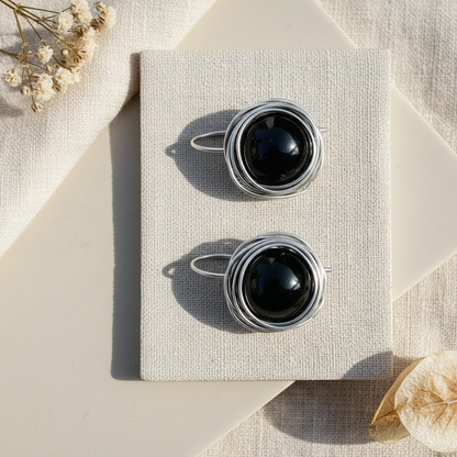 Flat lay náušnice s obsidiánom v striebornom drôtovanom hniezde na ľanovej látke – Harakka Jewls