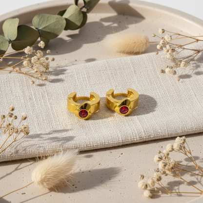 Zlaté náušnice s červeným kamienkom – luxusný flat lay Harakka