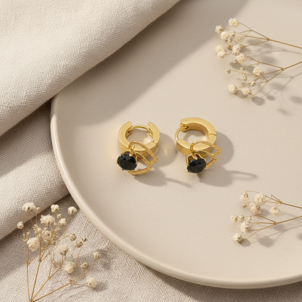 Zlaté náušnice s čiernym kamienkom – luxusný flat lay Harakka