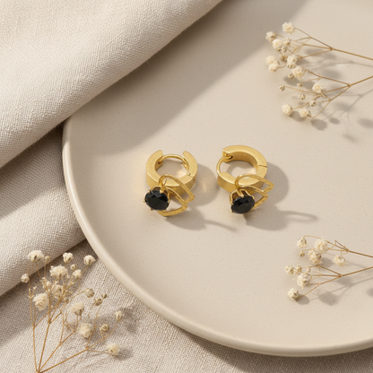Zlaté náušnice s čiernym kamienkom – luxusný flat lay Harakka