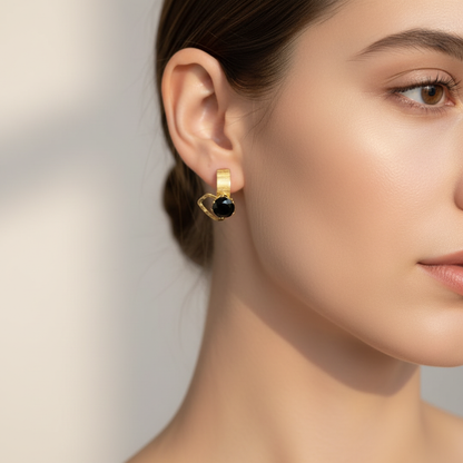 Zlaté náušnice s čiernym kamienkom na modelke – Harakka Jewls