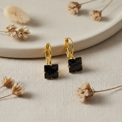 Zlaté náušnice s čiernym zirkónom – luxusný flat lay Harakka