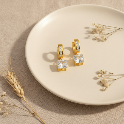 Zlaté náušnice s kockovým zirkónom – luxusný flat lay Harakka