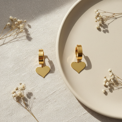 Zlaté náušnice so srdiečkovým príveskom – luxusný flat lay Harakka
